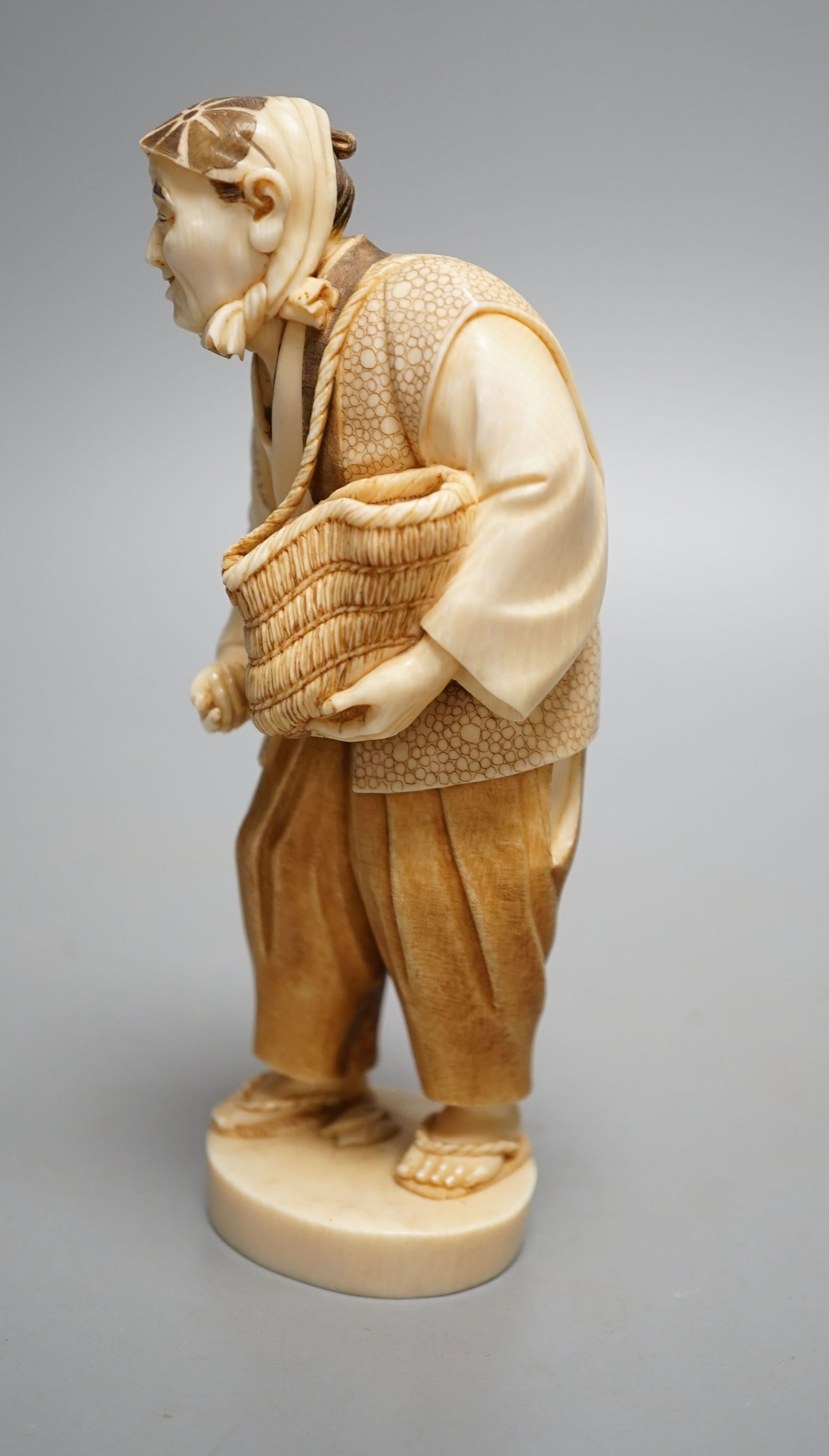 A Japanese ivory figure of a peasant farmer, Taisho/early Showa period, signed to a lacquer tablet - 17cm tall